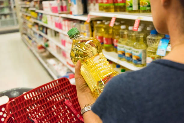 Woman in a shopping aisle holding a bottle of vegetable oil