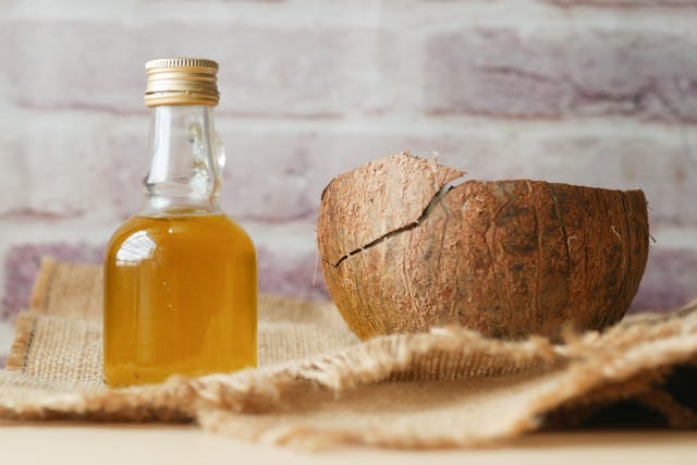 Coconut oil on a table next to half a coconut