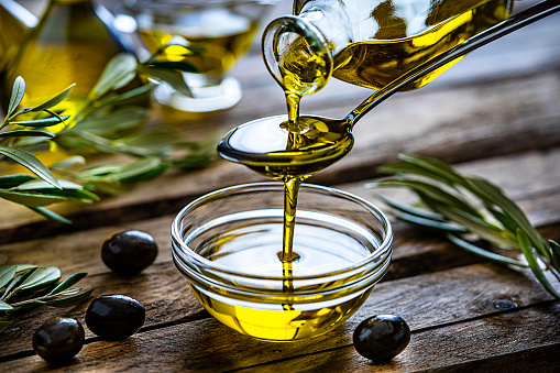 Olive oil being poured into a small glass bowl