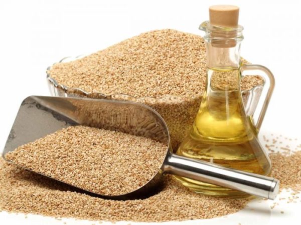 Bottle of sesame oil next to a food spade of sesame seeds